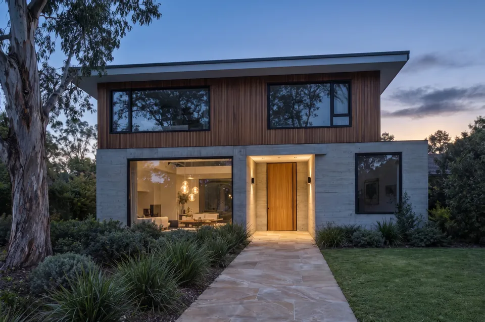 The same house edited to dusk, with only its existing lights switched on.